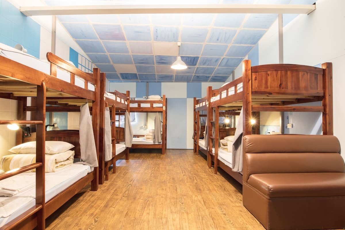 A bunk room with wooden bunk beds, a brown leather bench, and a ceiling with a grid pattern.