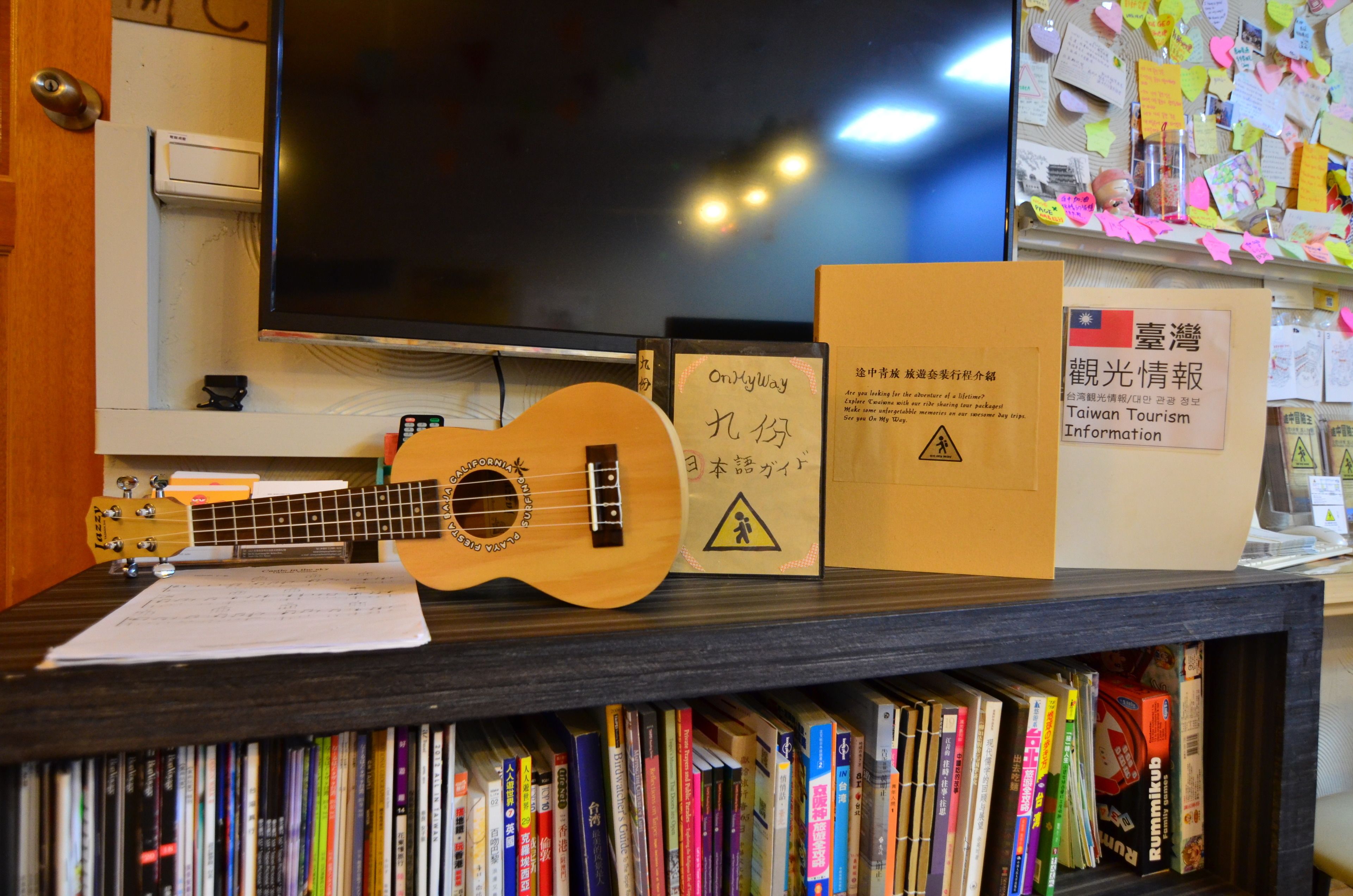 Une étagère avec une guitare, un livre et un panneau contenant des informations sur le tourisme à Taïwan.