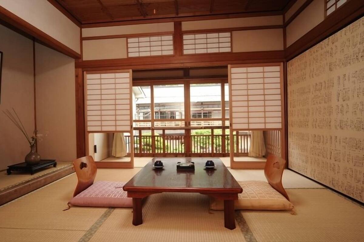Una habitación tradicional japonesa con suelo de tatami, una mesa de madera baja y puertas correderas shoji.