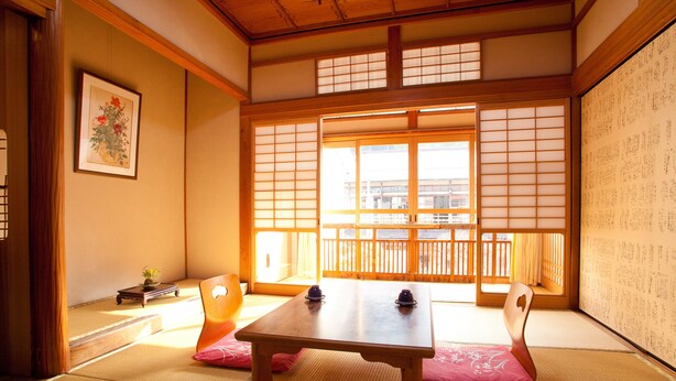 Ein traditioneller japanischer Raum mit Tatami-Böden, einem niedrigen Holztisch und Shoji-Schiebetüren.