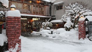 Ein mit Schnee bedecktes Gebäude mit Ziegelpfeilern und einer Holzfassade.