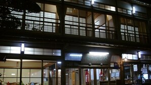 Ein traditionelles japanisches Gebäude mit mehreren Stockwerken und großen Fenstern, mit einem Schild mit japanischen Schriftzeichen.