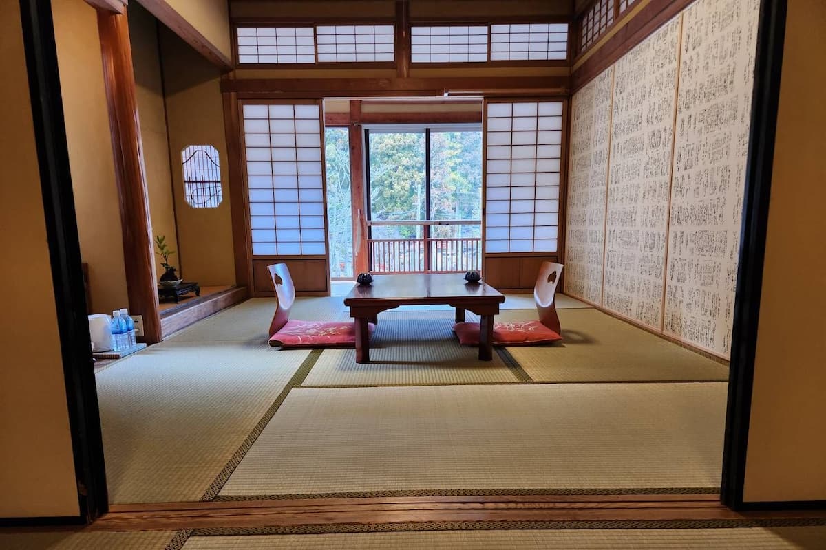 Une pièce de style japonais traditionnel, avec un sol recouvert de tatamis, une table basse et des portes coulissantes.
