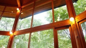 Une cabane en bois dotée de grandes fenêtres et d’un plancher en bois.