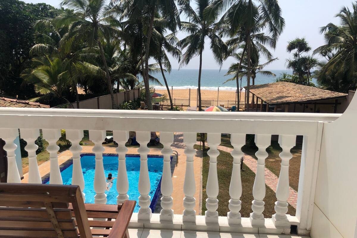 Un balcon avec vue sur une piscine, des palmiers et une plage.