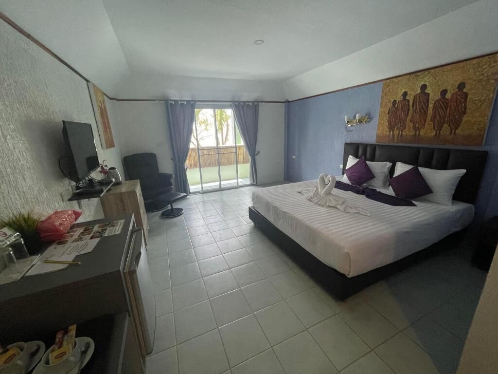 Quarto de hotel com cama, escrivaninha, cadeira e um quadro na parede.