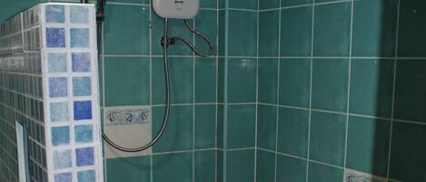 Un baño pequeño con azulejos verde azulado, una ducha y un inodoro.