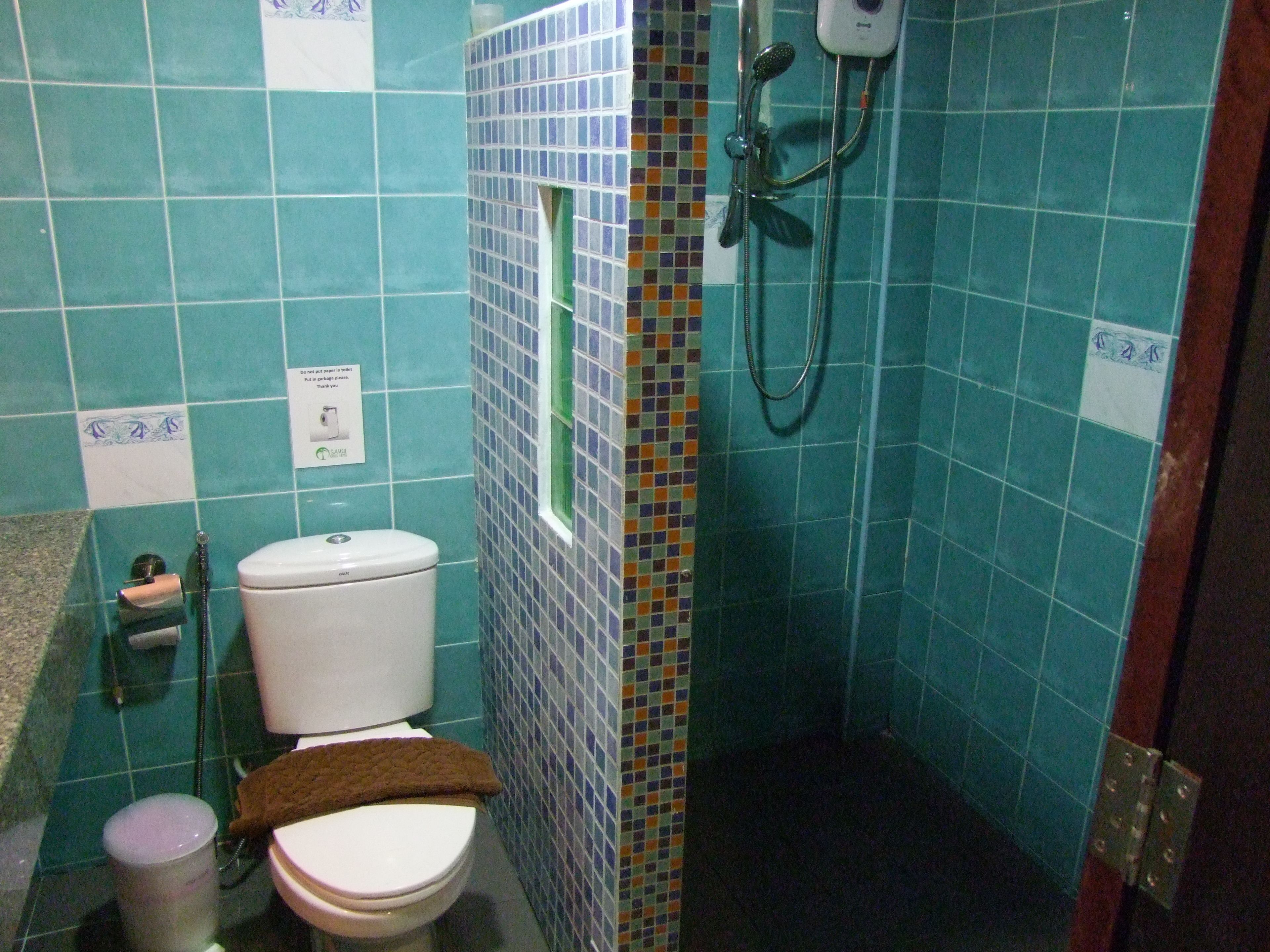 A bathroom with a toilet, a shower, and a sink.