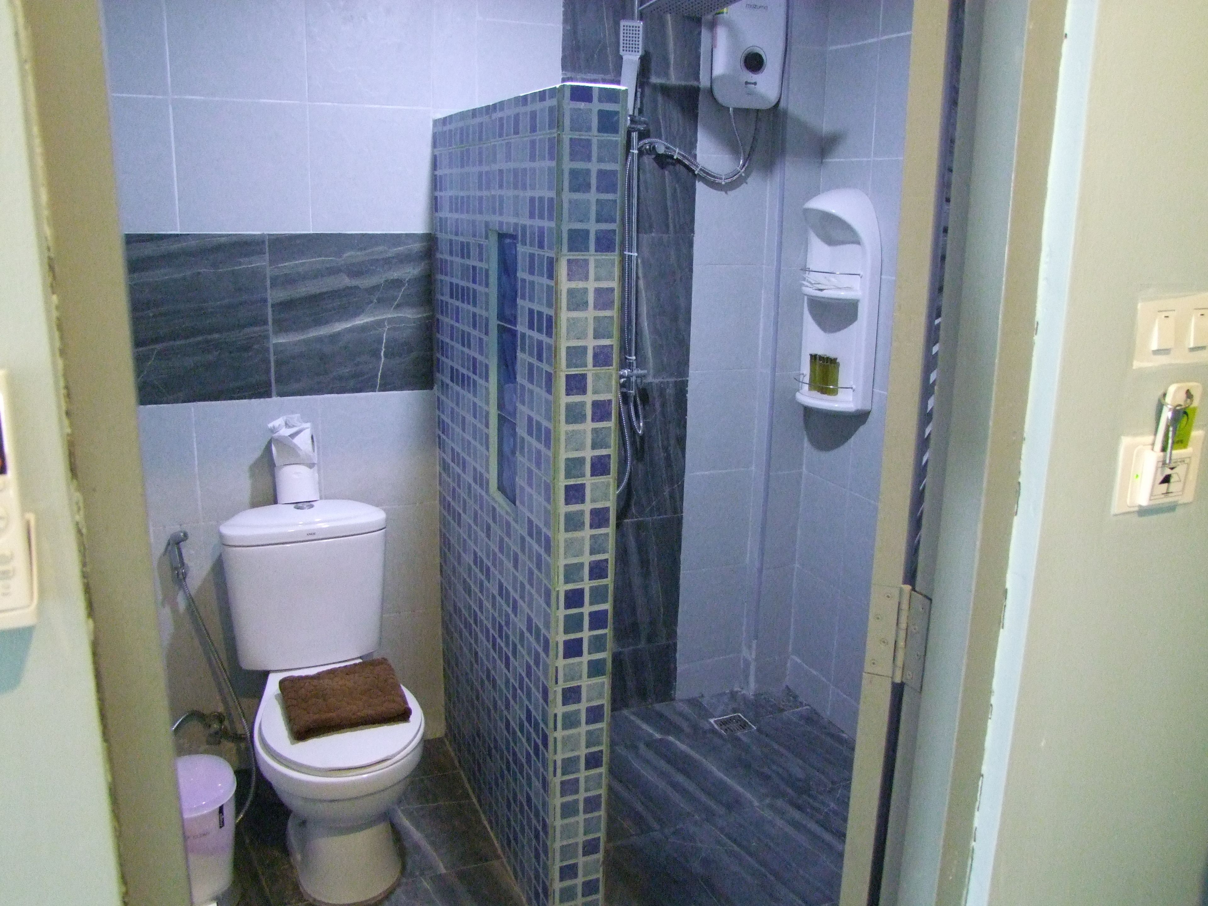 A bathroom with a toilet, a shower, and a sink.