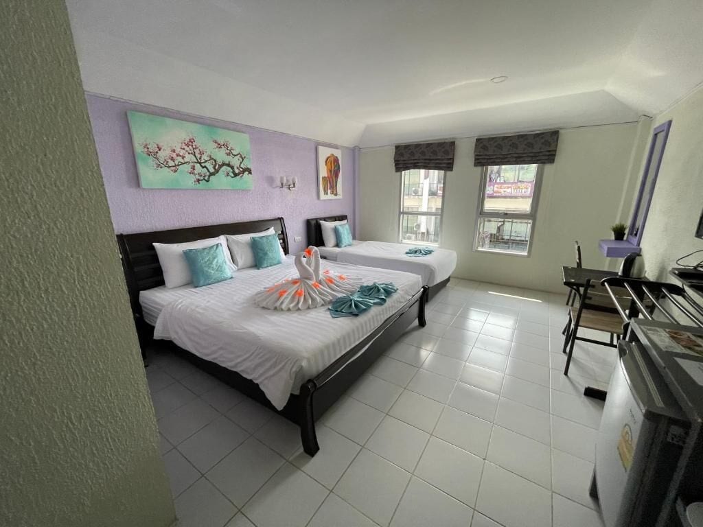 Una habitación de hotel con dos camas, un escritorio y una ventana que da a la calle.