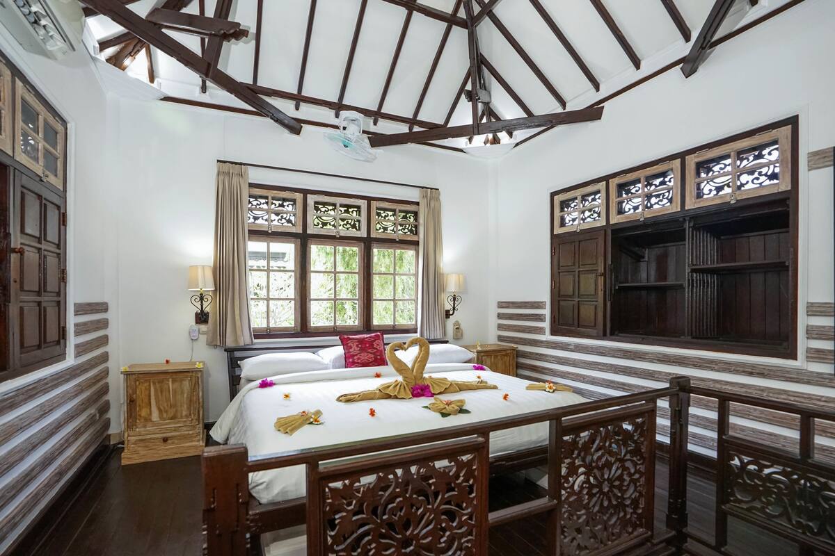 A traditional room with a bed, wooden furniture, and decorative window grills.