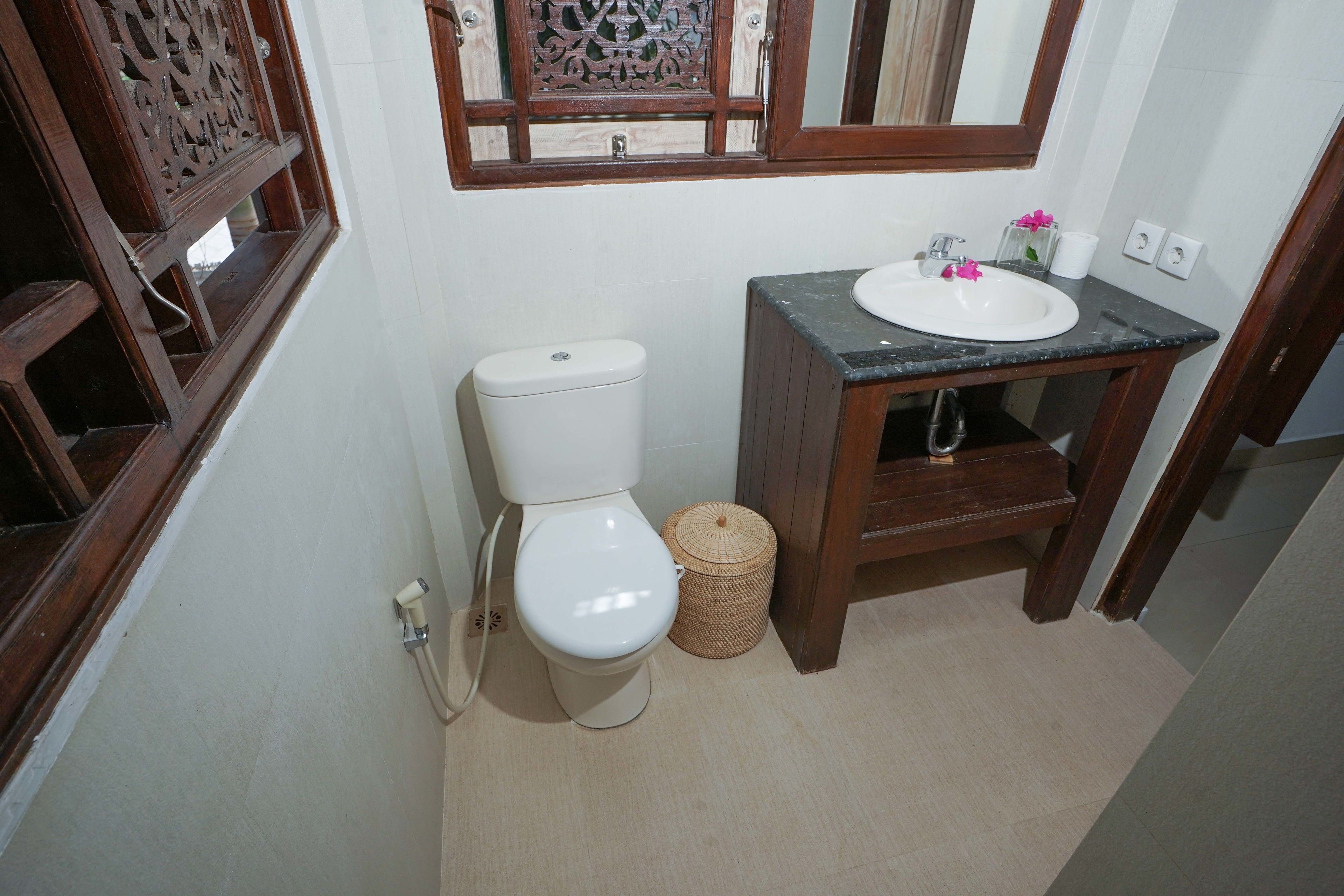 A bathroom with a toilet, sink, and a decorative mirror.