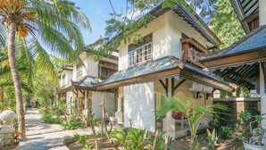 A traditional house with a tiled roof, a stone pathway, and various tropical plants. - Martas Hotel Gili Trawangan (Gili Trawangan)