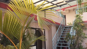 Un espacio al aire libre cubierto con una escalera, plantas en macetas y una puerta.