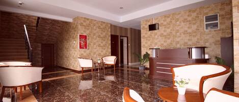 A lobby with a marble floor, a staircase, and a reception desk.