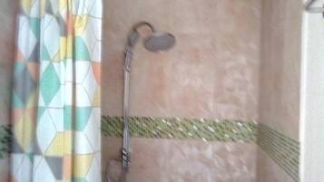 A shower area with a patterned curtain, a handheld showerhead, and a tiled wall.