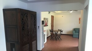 Una habitación con una mesa de comedor y sillas, un sofá, un armario de madera y un ventilador de techo.
