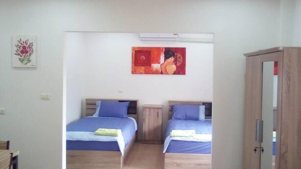 Una habitación con dos camas, un sofá azul, un armario de madera y un cuadro en la pared.