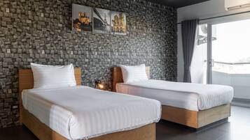 Habitación de hotel con dos camas de madera, una pared de piedra y un ventanal con vistas.