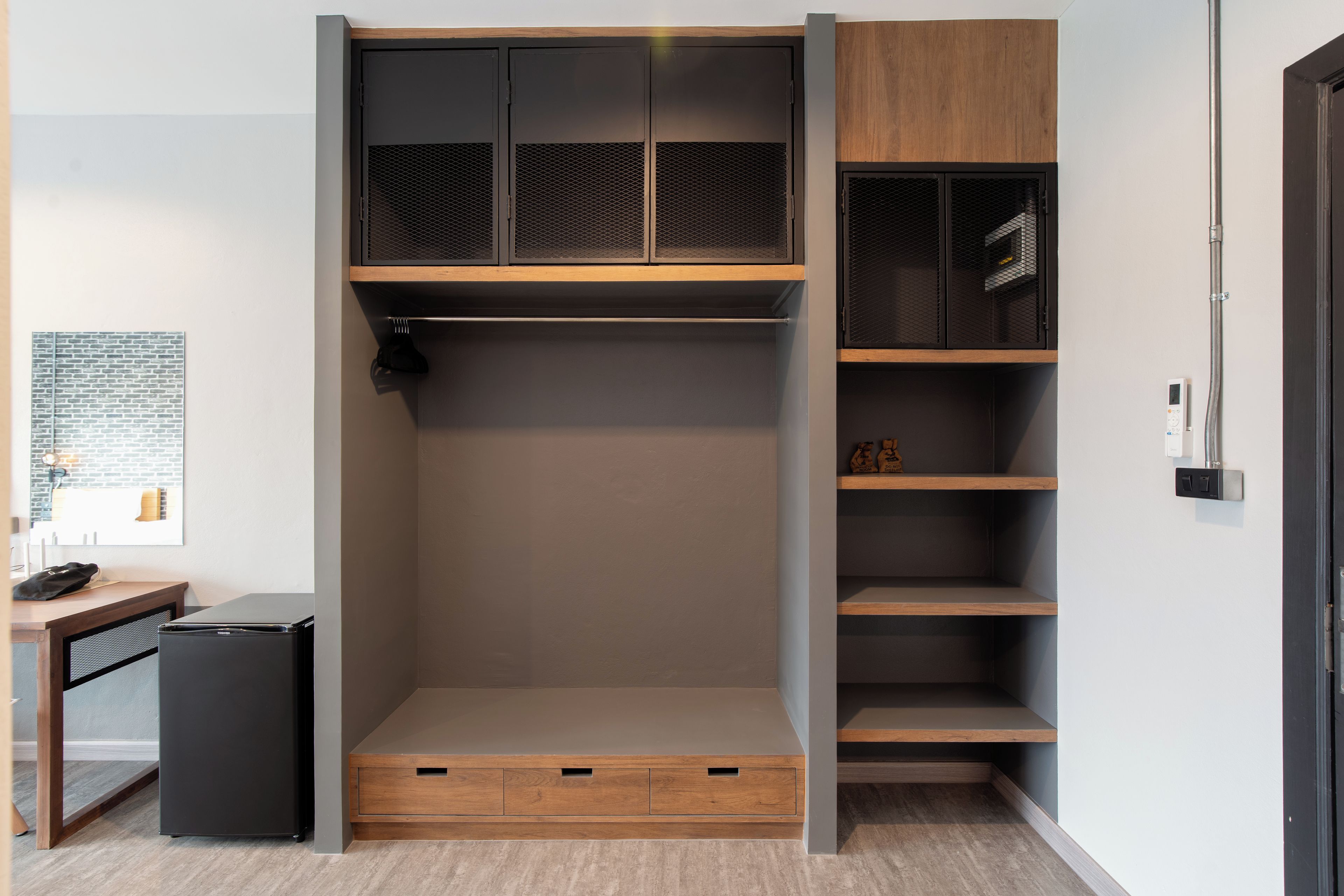 A walk-in closet with a sliding door, multiple shelves, and a small desk with a computer.