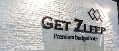 A white brick wall with the text "GET ZLEEP Premium budget hotel" and a logo above it.