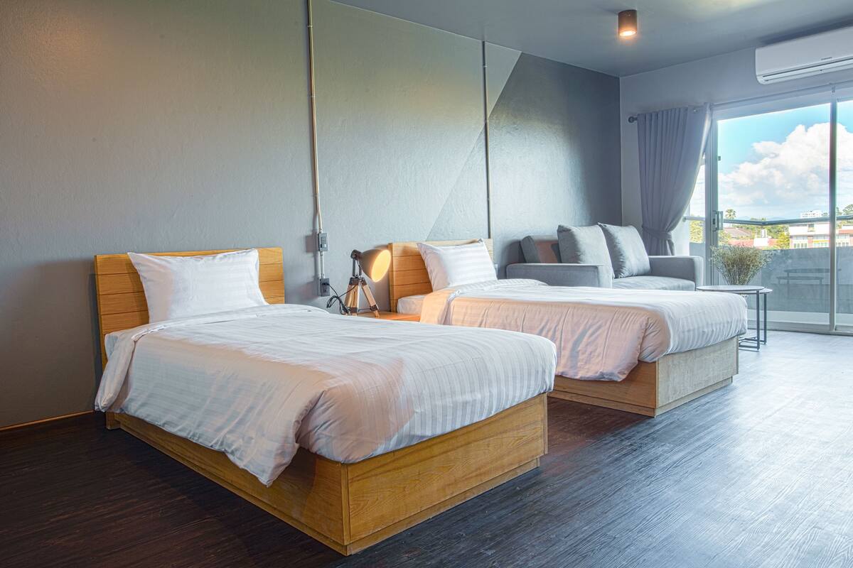 Een hotelkamer met twee bedden, een bureau en een groot raam met uitzicht.