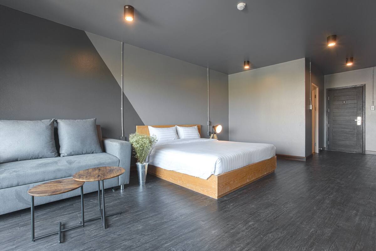 Een moderne slaapkamer met een bed, een bank, een kleine tafel en een potplant.