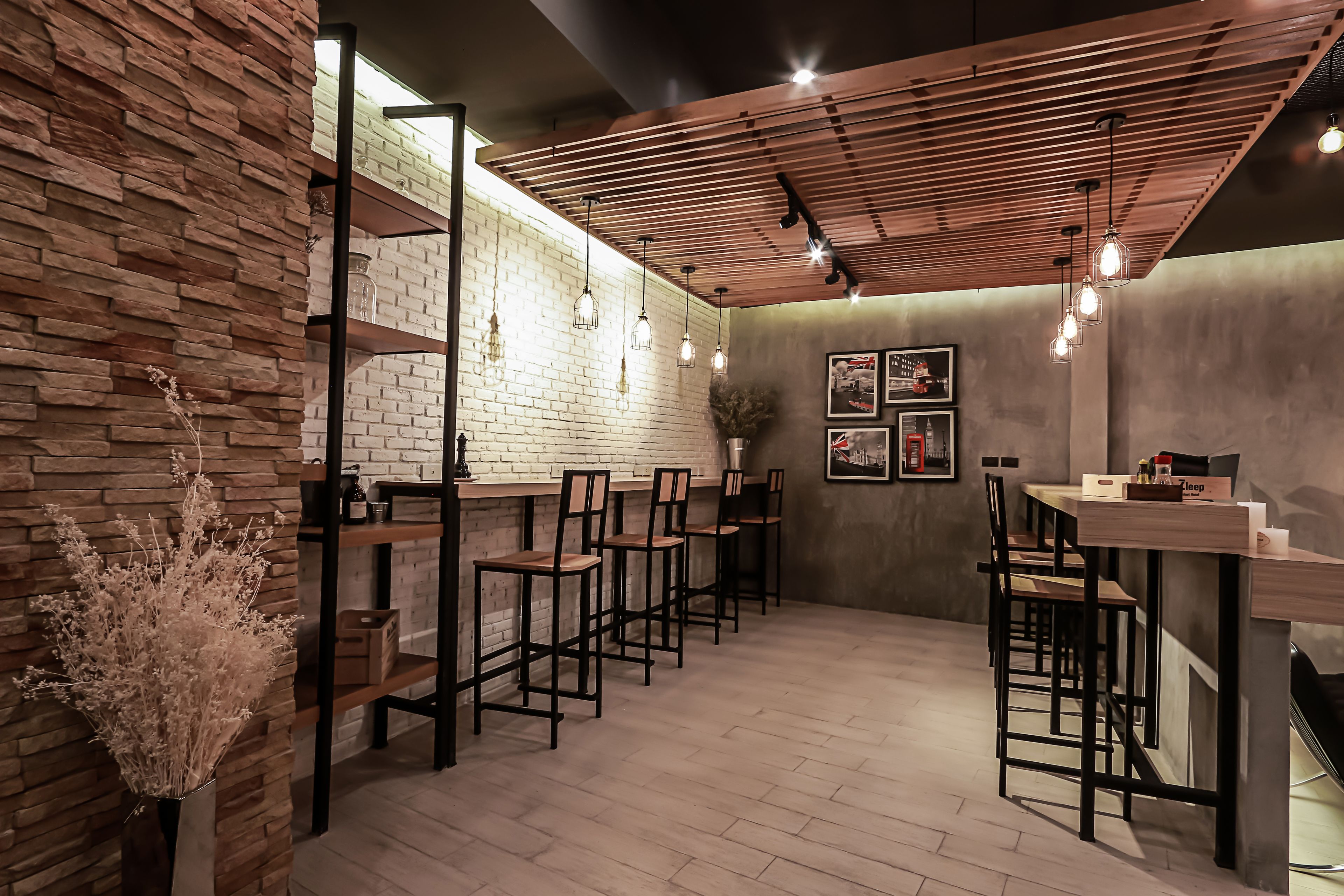 Un café moderno con paredes de ladrillo visto, taburetes de madera y lámparas colgantes.