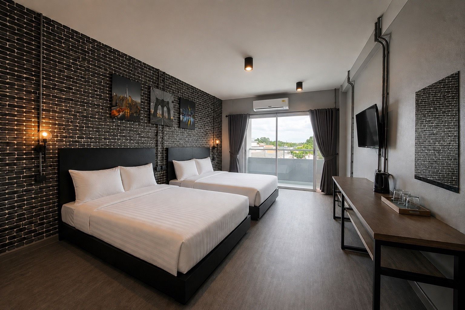 A hotel room with two beds, a desk, a TV, and a balcony with a city view.