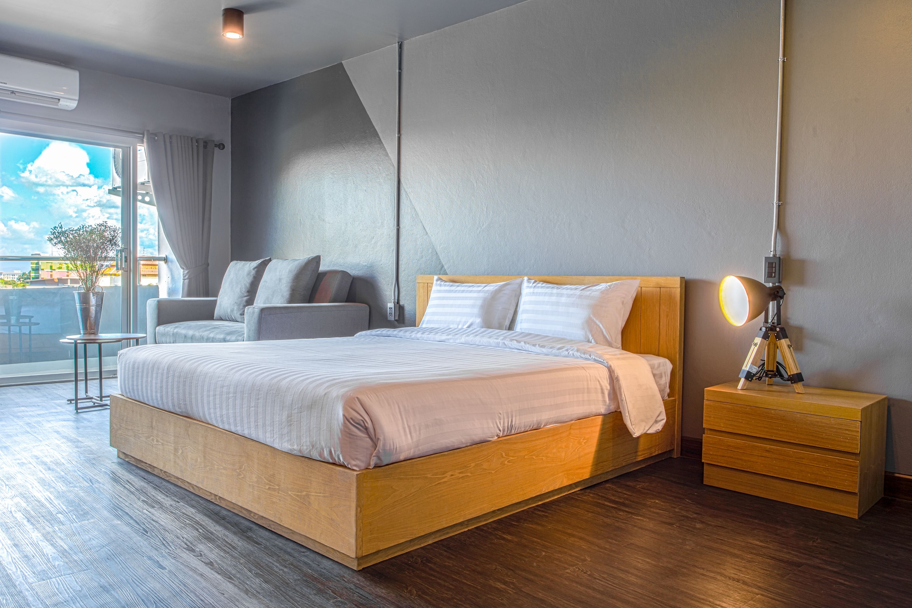 A modern bedroom with a large bed, a wooden nightstand, and a bedside lamp.