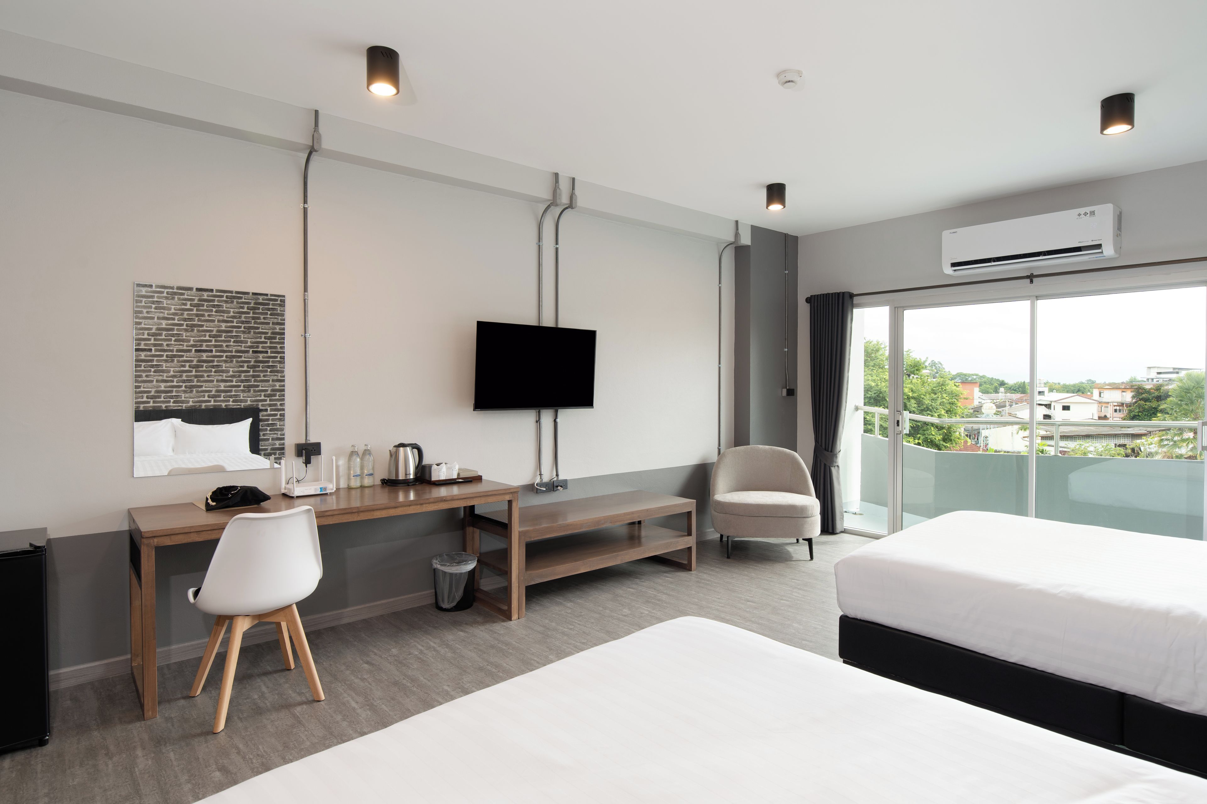 Habitación de hotel moderna con cama, escritorio con silla, televisor y vista panorámica de la ciudad.