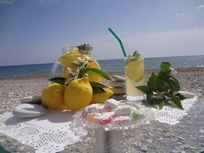 Une table avec des citrons, une carafe, un verre avec une paille et une assiette de bonbons multicolores, le tout sur une plage.