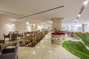 A spacious dining area with multiple tables and chairs, a central decorative column, and pendant lighting. - Diamond Bay Hotel (Nha Trang)