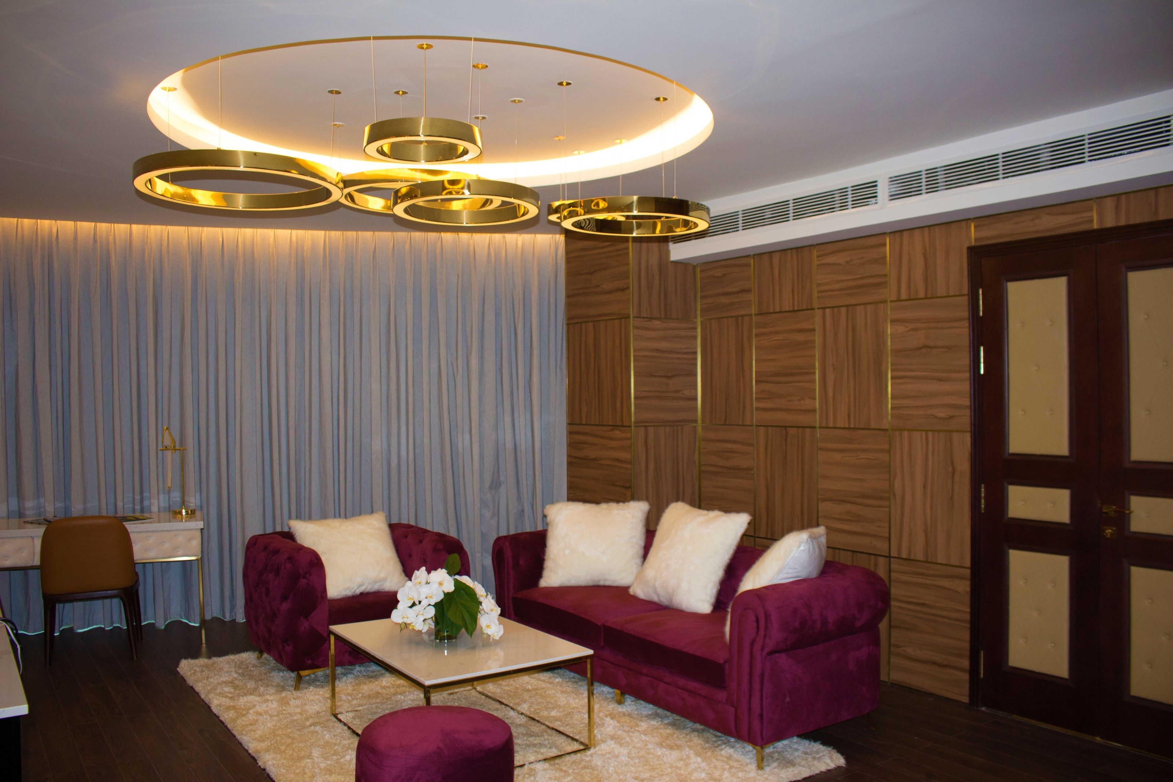 A modern living room with a red velvet sofa, a coffee table, and a decorative chandelier.