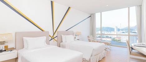 Une chambre d’hôtel avec deux lits, un bureau avec une lampe, une chaise et une vue sur la ville.
