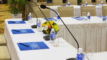 A conference table with microphones, water bottles, and blue name cards.