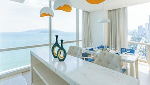 A modern dining area with a city view, a large window, and a table set for dining. - Diamond Bay Hotel (Nha Trang)