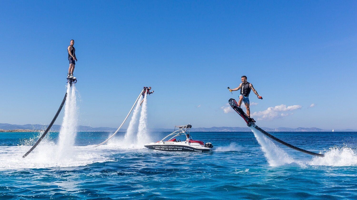 Three jet skis with riders performing stunts in the water.