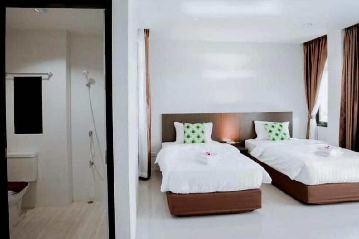 Une chambre d’hôtel avec deux lits, une douche et une fenêtre avec des rideaux.
