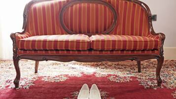 Un sofá de estilo vintage con estampado a rayas y respaldo circular, sobre una alfombra roja con diseño floral.