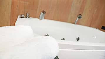 Una bañera blanca con dos llaves y una toalla al lado.