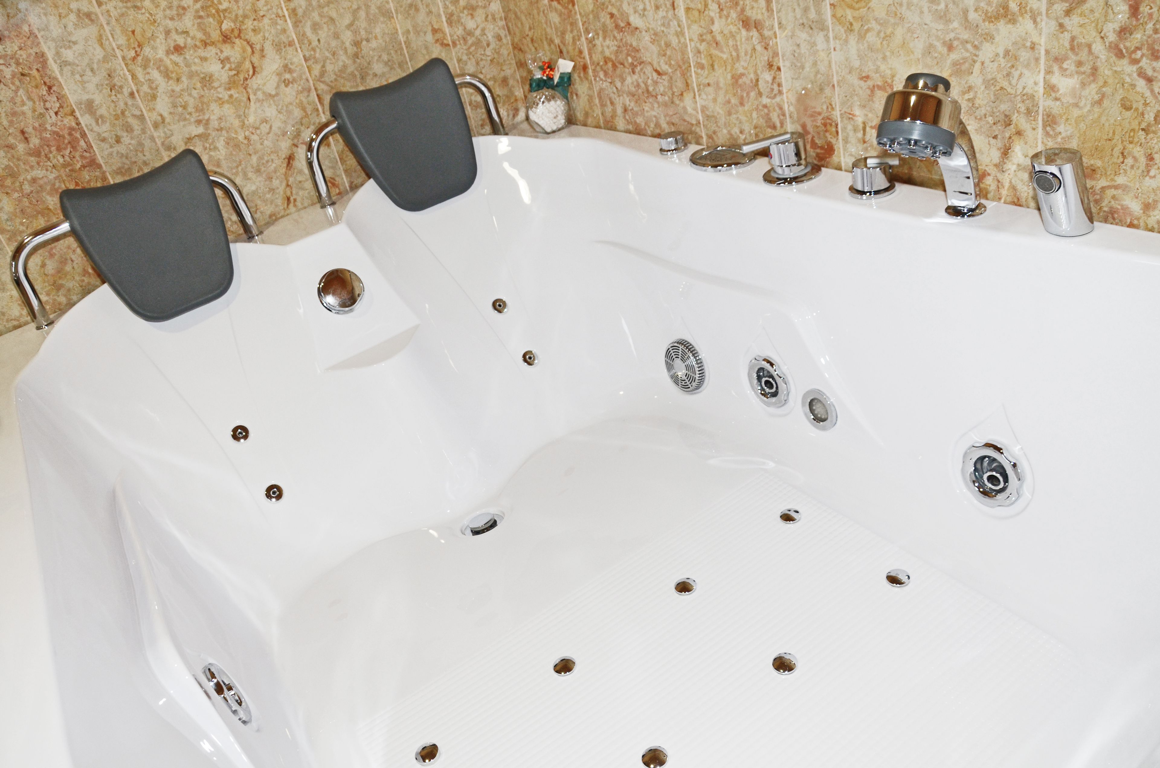 A white hot tub with multiple jets, a built-in seat, and a control panel.