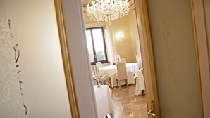 Une salle à manger élégamment décorée, avec un lustre, des nappes blanches et des chaises.