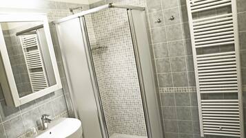 A bathroom with a glass-enclosed shower, a white sink, and a towel rack.