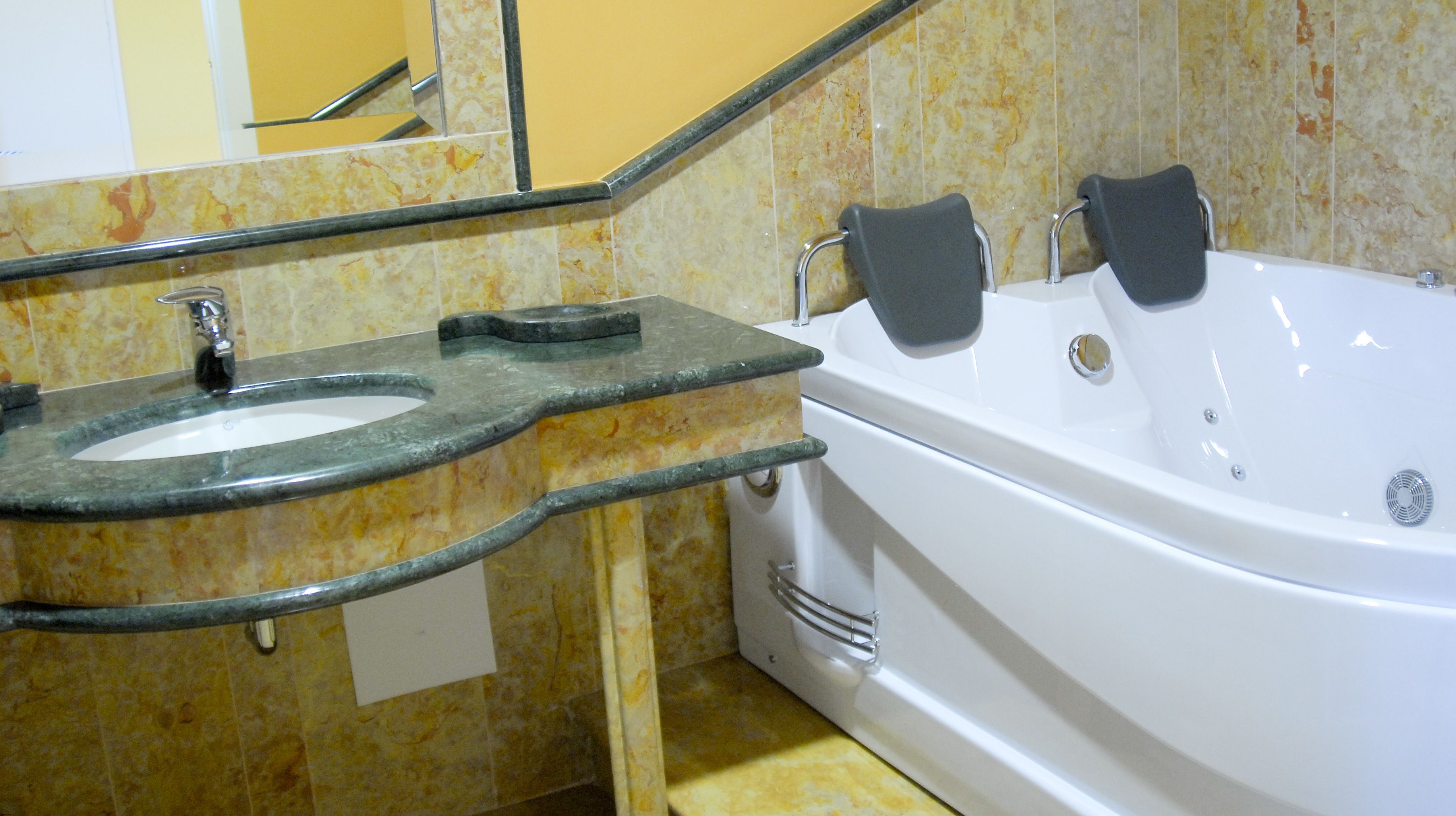 Un baño con lavamanos de mármol, una bañera y un espejo.