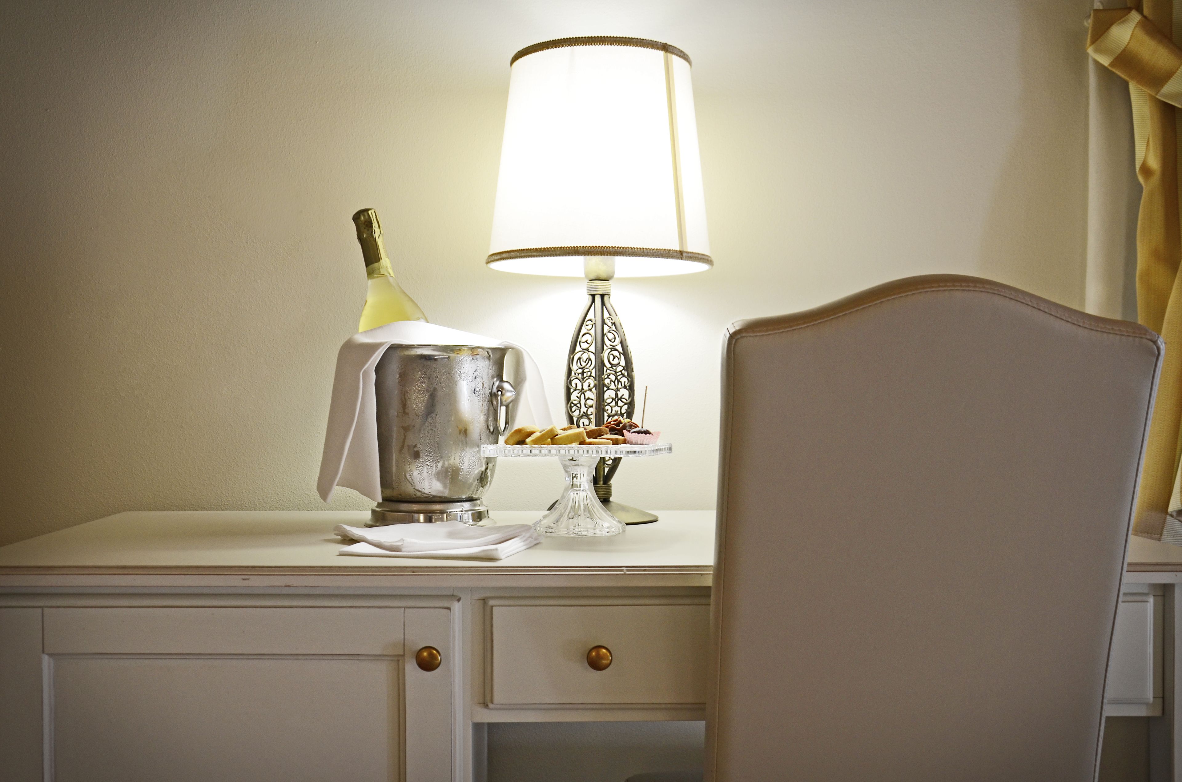 A table with a bottle of champagne, a metal pitcher, and a plate of cookies.