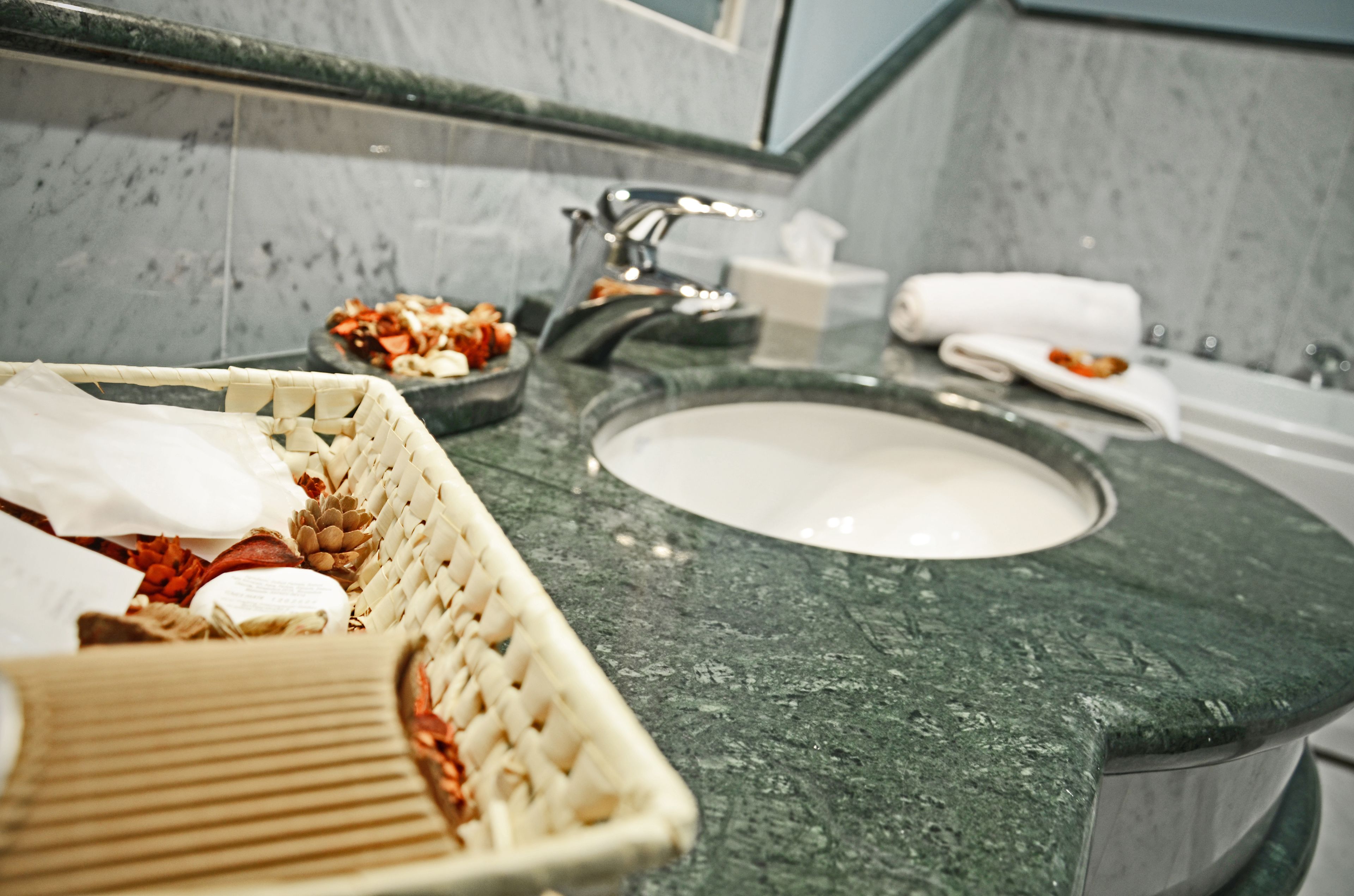 A bathroom with a marble sink, a woven basket with toiletries, and a small dish of snacks.