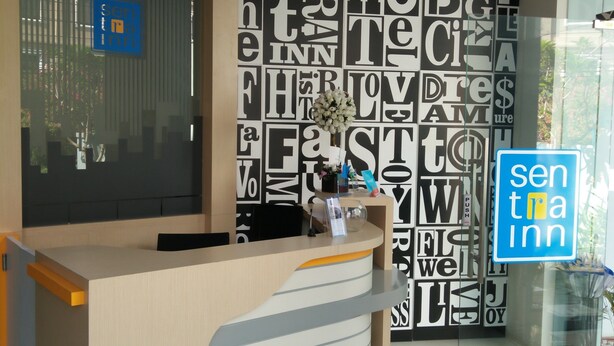 Una recepción de hotel con un diseño moderno, una mampara de vidrio y un letrero que dice 'senna inn'.
