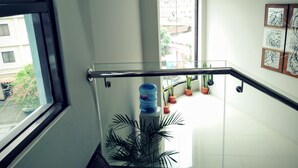 Un interior moderno con barandilla de cristal, plantas en macetas y obras de arte en las paredes.