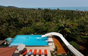 A pool with a water slide, surrounded by lush greenery and a view of the ocean. - 6 Bedroom Waterslide Villa SDV146-By Samui Dream Villas (Koh Samui)